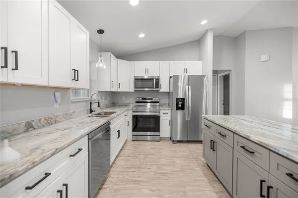 a kitchen with kitchen island granite countertop a sink appliances cabinets and counter space