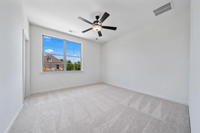 an empty room with windows and ceiling fan