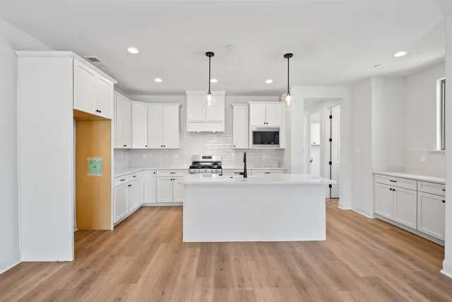 a large kitchen with cabinets wooden floor and stainless steel appliances