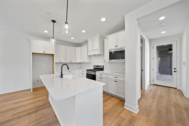 a kitchen with cabinets a sink a center island and stainless steel appliances