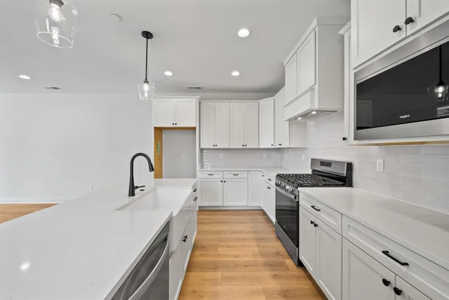 a kitchen with stainless steel appliances a sink a stove top oven a counter space and cabinets
