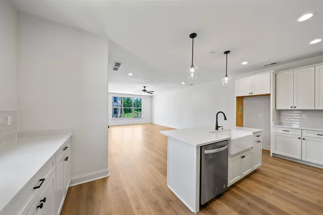 a large white kitchen with a sink a window and stainless steel appliances