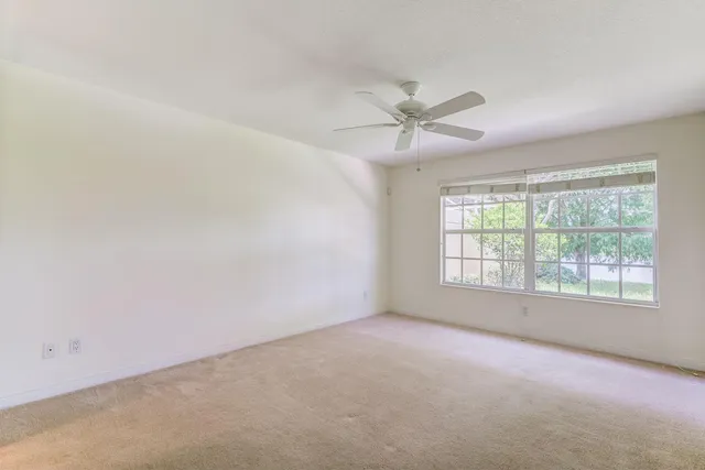 an empty room with a window and a fan