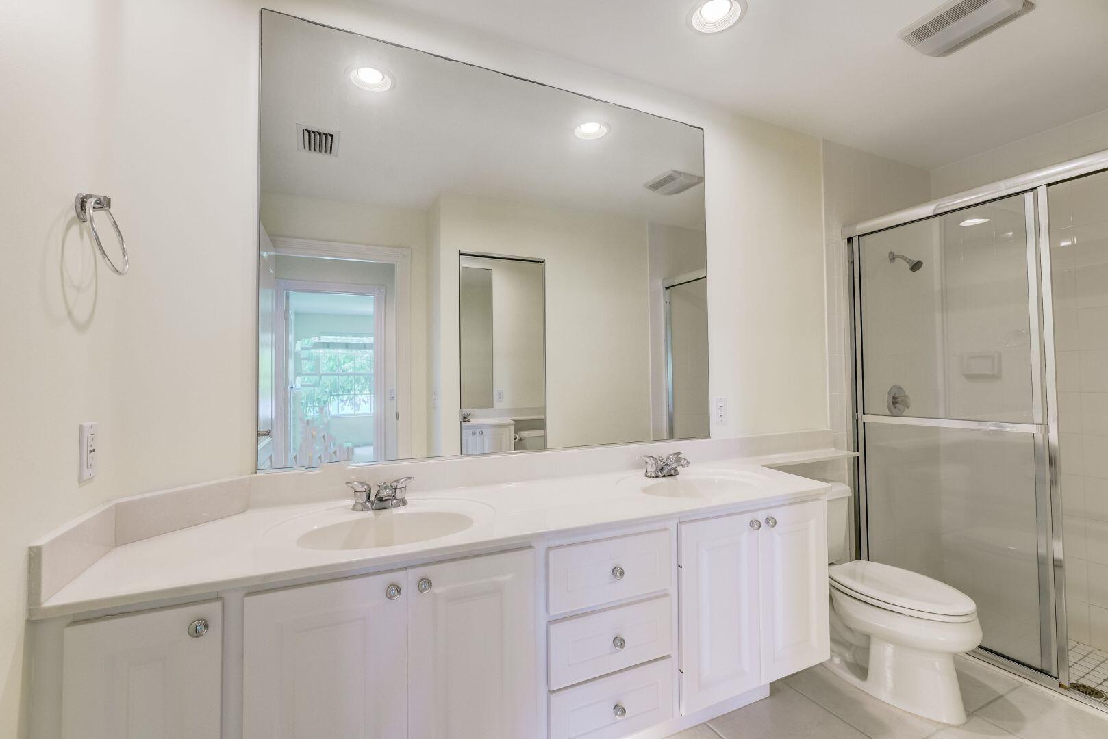 923 Magdalena Road Palm Beach Gardens, FL 33410 - Photo 14 of 47 a bathroom with a double vanity sink a toilet and a mirror