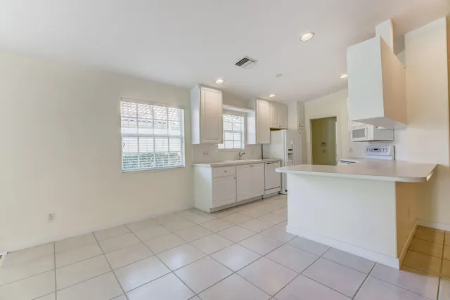 a kitchen with white cabinets and window