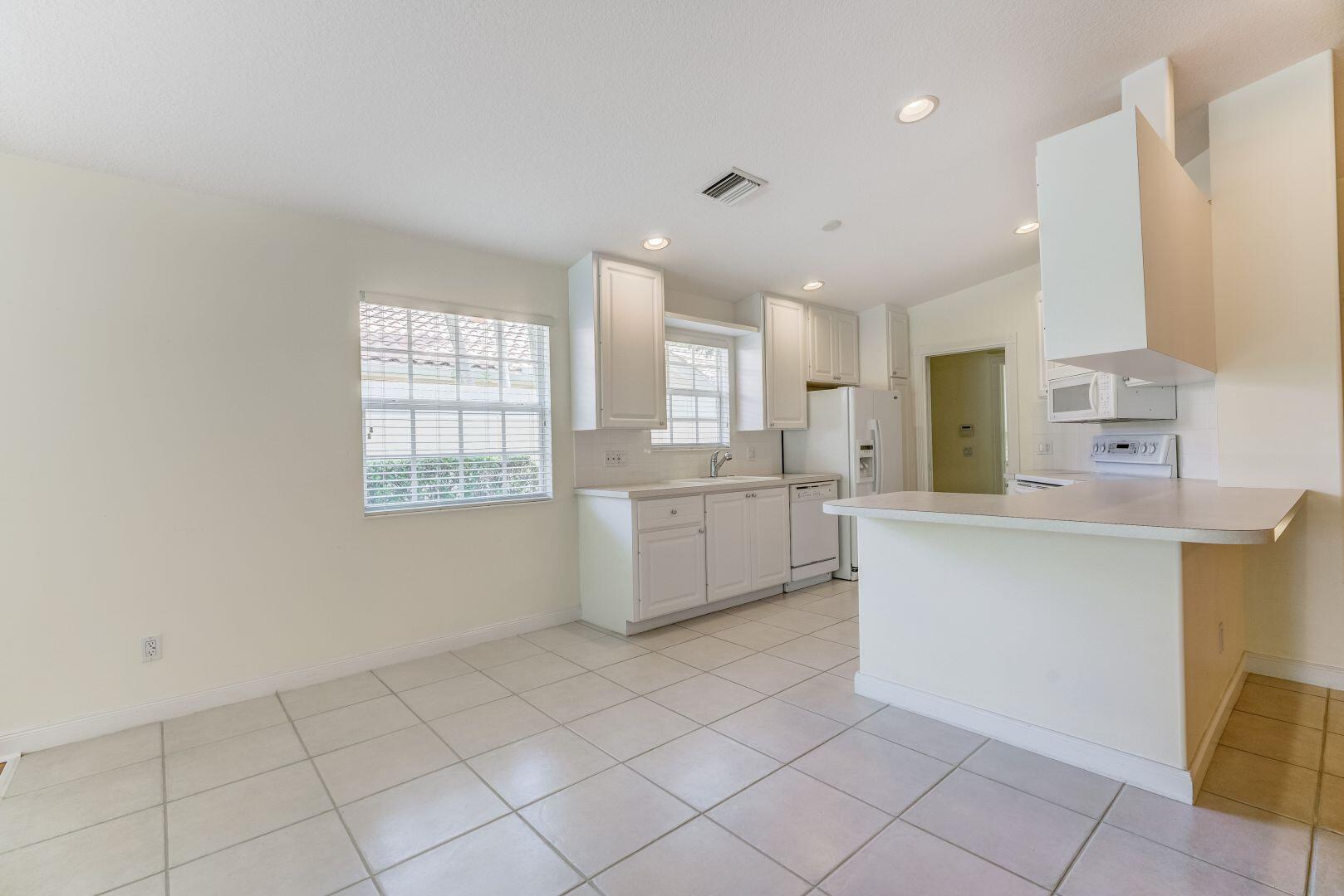 923 Magdalena Road Palm Beach Gardens, FL 33410 - Photo 21 of 47 a kitchen with white cabinets and window