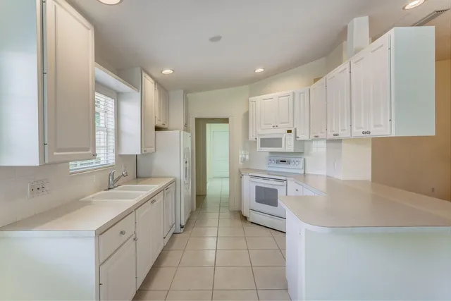 a kitchen with kitchen island white cabinets appliances and a sink