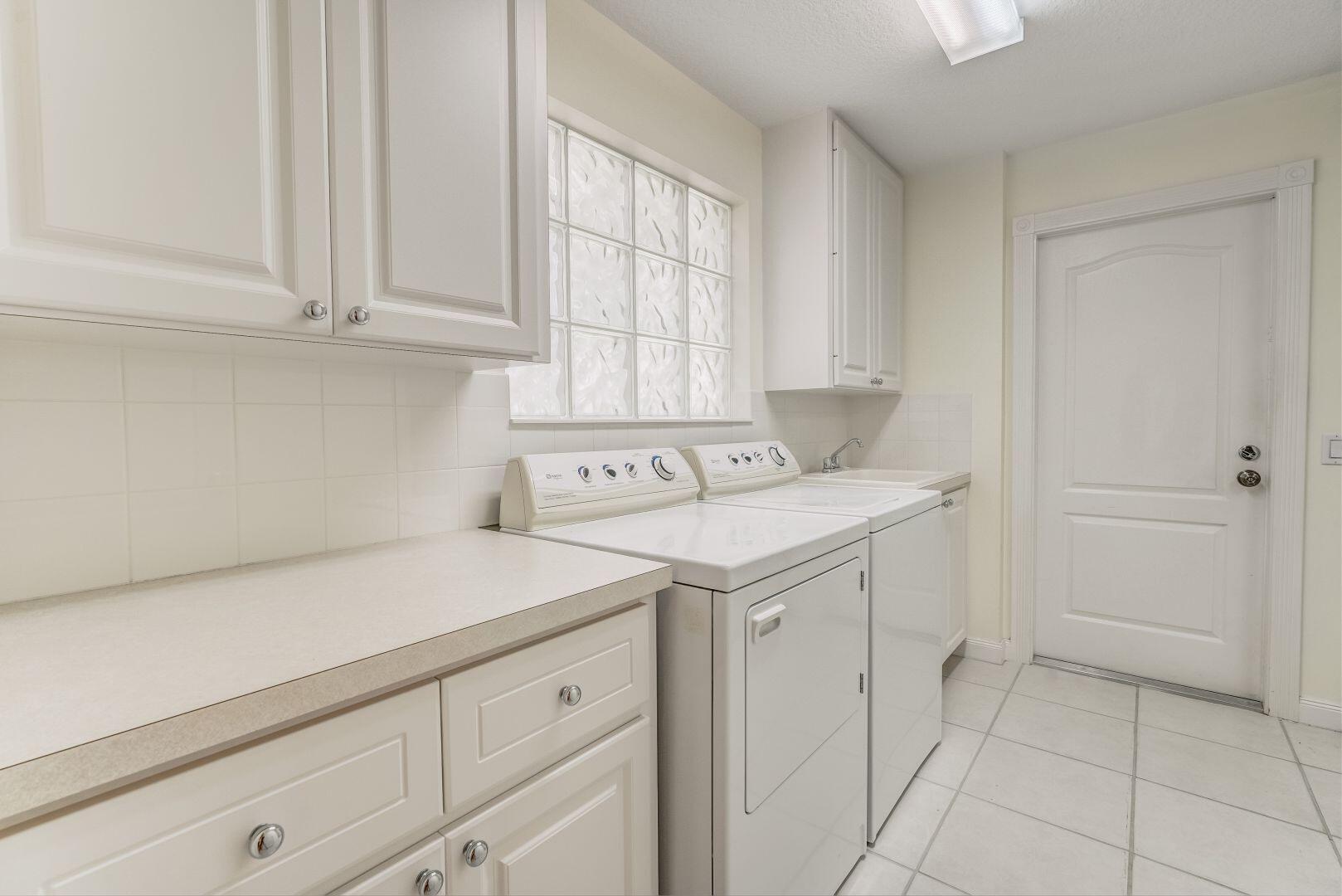 923 Magdalena Road Palm Beach Gardens, FL 33410 - Photo 25 of 47 a utility room with cabinets washer and dryer