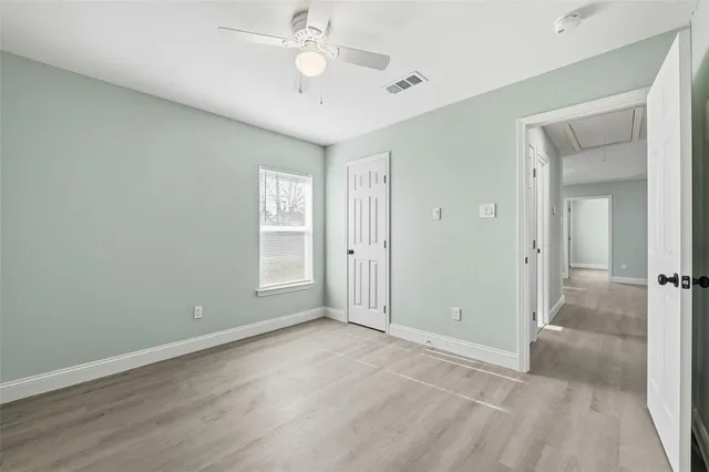 an empty room with wooden floor and fan