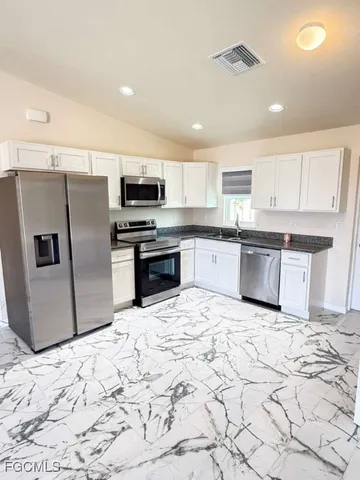a kitchen with stainless steel appliances granite countertop a refrigerator sink and cabinets
