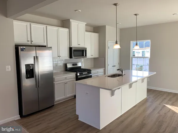 a kitchen with stainless steel appliances a refrigerator a sink a stove a microwave and wooden floor