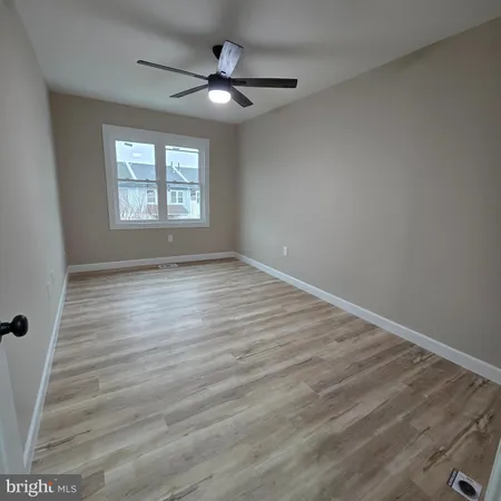an empty room with wooden floor fan and windows
