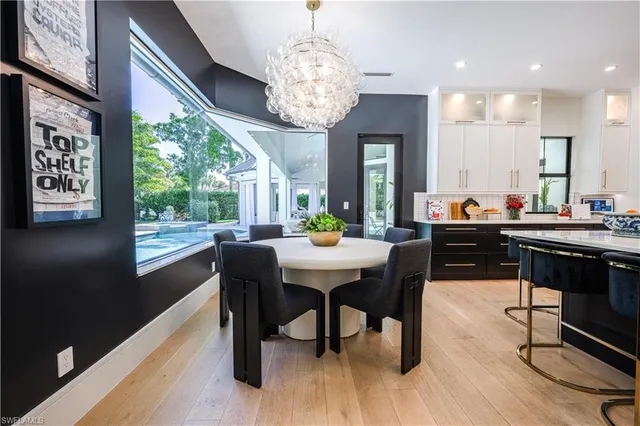 a dining room with wooden floor a chandelier a wooden table and chairs