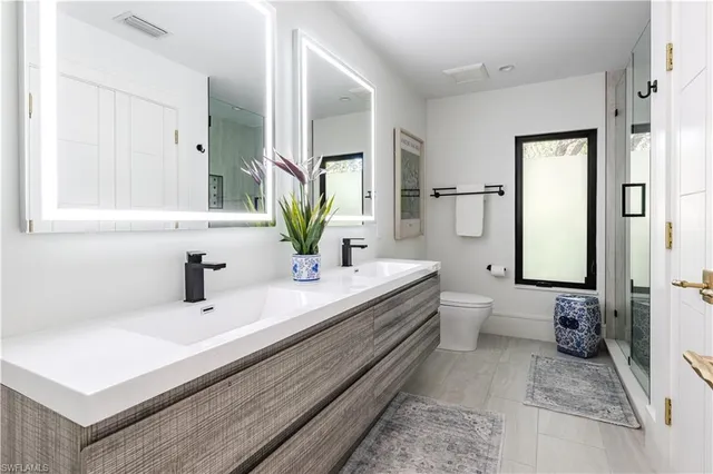 a bathroom with a double vanity sink mirror and toilet