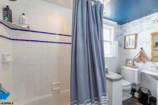 a bathroom with a sink a toilet a window and shower