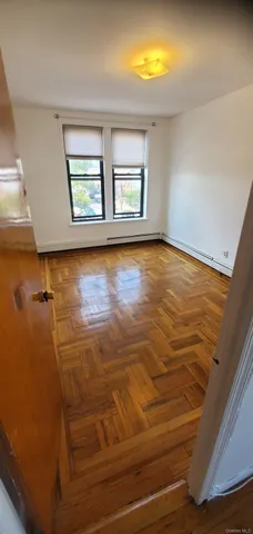 a view of an empty room with window and wooden floor