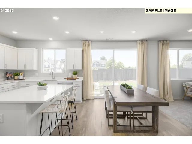 a view of kitchen with granite countertop a dining table chairs and white cabinets