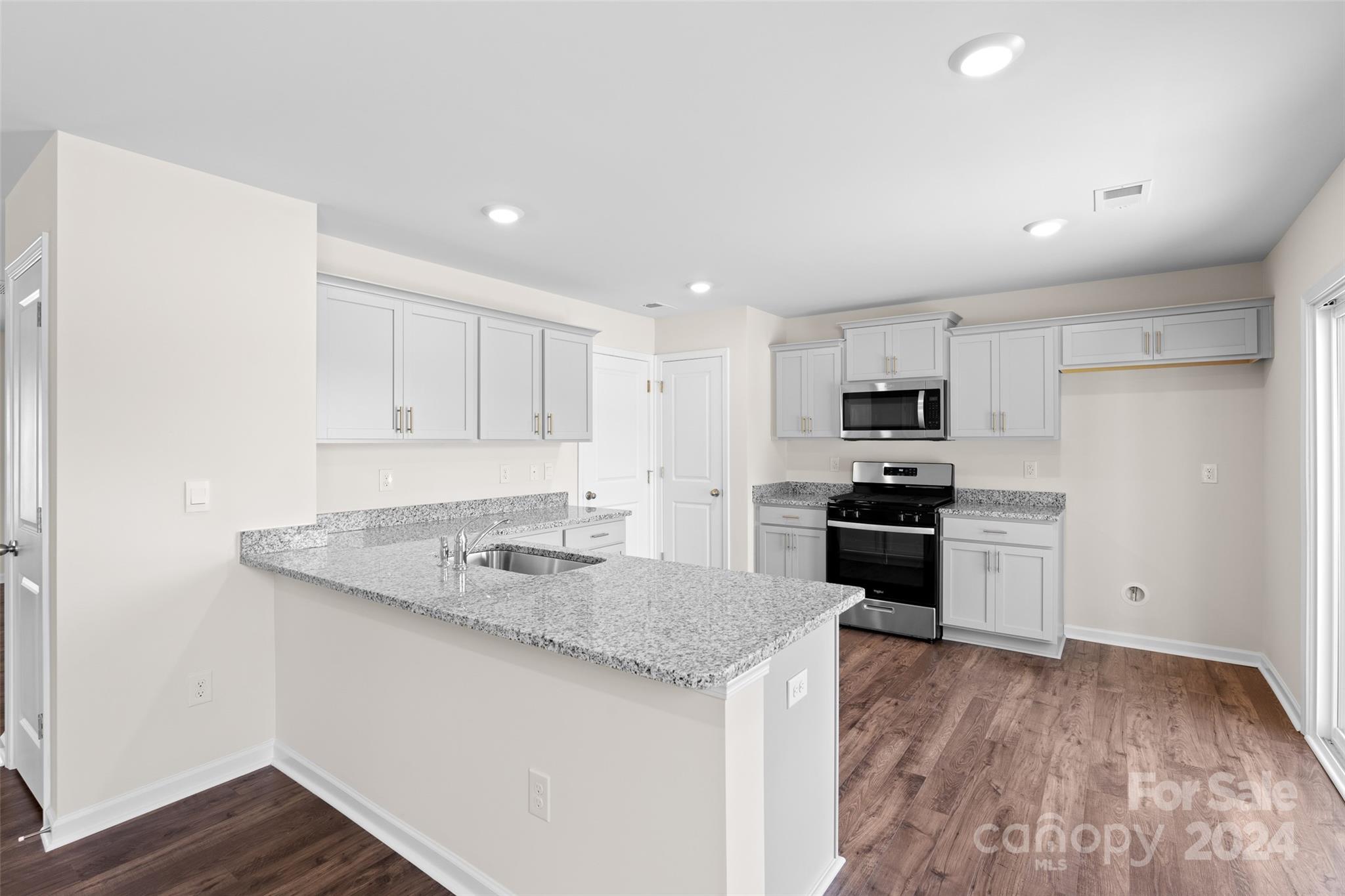 100 Callie River Clyde, NC 28721 - Photo 7 of 22 a kitchen with a sink a stove a refrigerator and white cabinets
