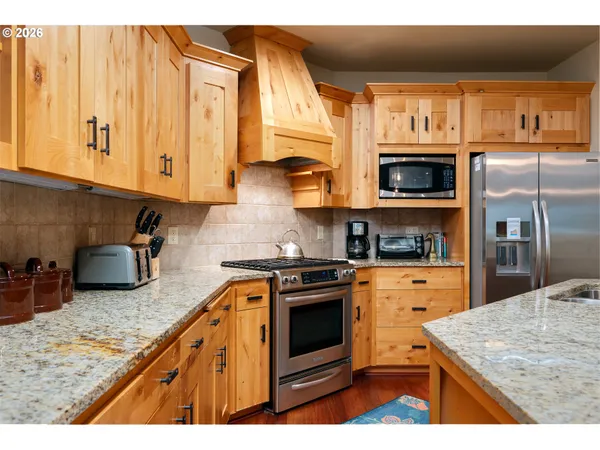 a kitchen with stainless steel appliances granite countertop a stove a sink and a microwave