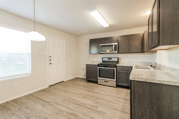 a kitchen with granite countertop a stove a sink and a microwave