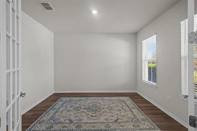 a kitchen with stainless steel appliances granite countertop a stove top oven a refrigerator a sink and white cabinets with wooden floor