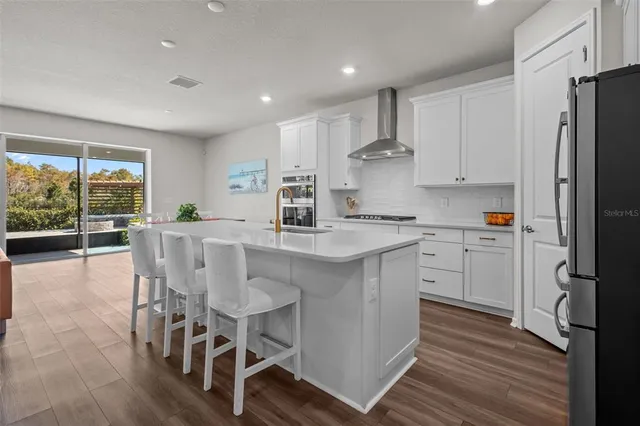 a large kitchen with stainless steel appliances kitchen island granite countertop a stove and a sink