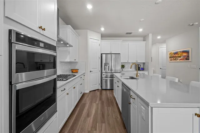 a kitchen with stainless steel appliances a stove a sink a refrigerator and cabinets