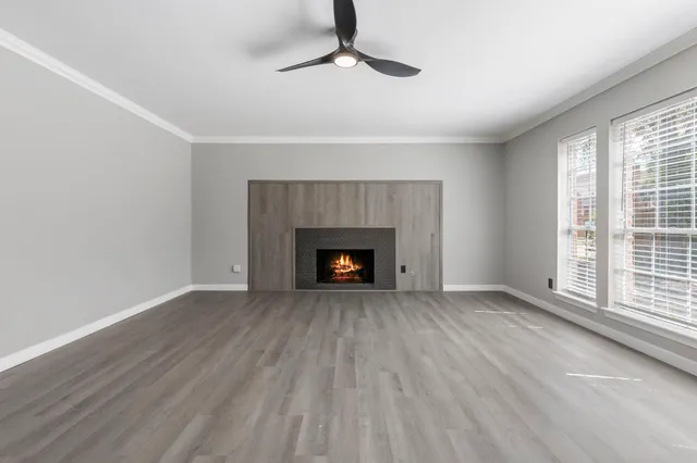 a view of an empty room with wooden floor fireplace and a window