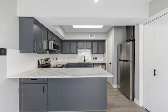 a kitchen with stainless steel appliances granite countertop a refrigerator a stove a sink and a microwave