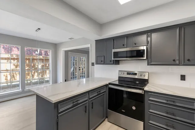 a kitchen with kitchen island granite countertop a stove and a sink