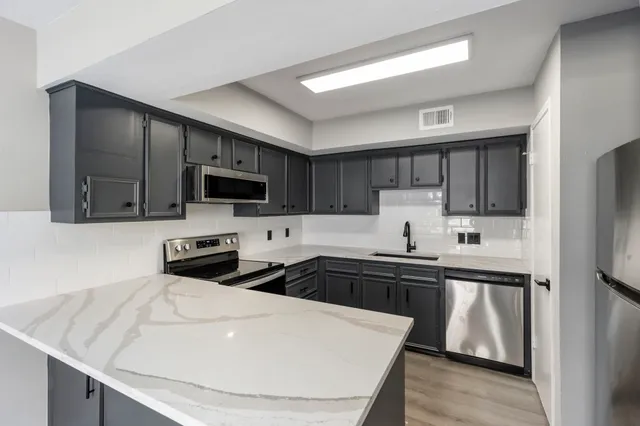 a kitchen with stainless steel appliances a stove sink microwave and refrigerator