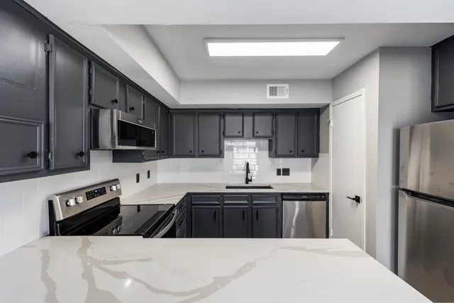 a kitchen with stainless steel appliances a sink a stove a refrigerator cabinets and a counter top space