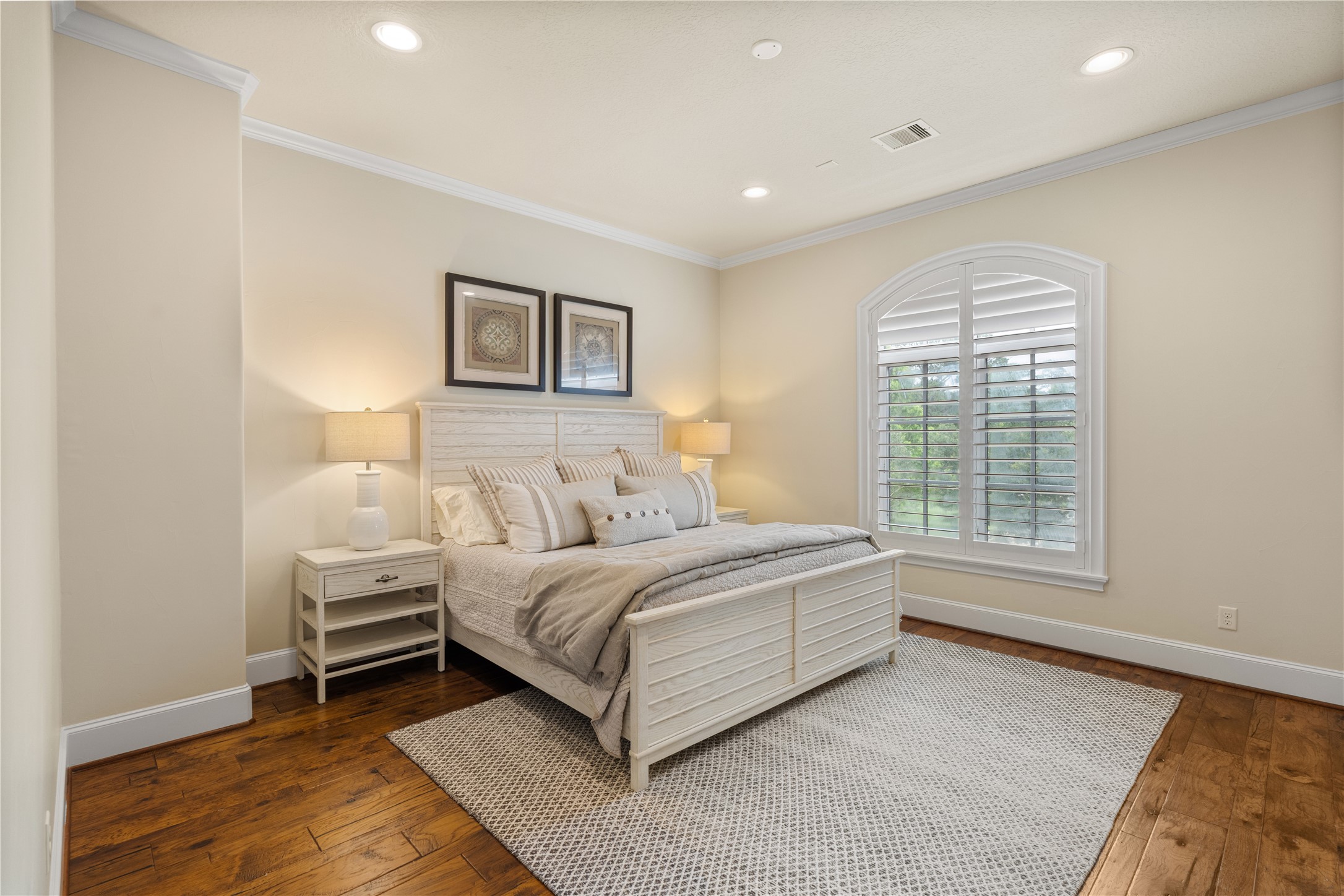 12349 Longmire Trace Conroe, TX 77304 - Photo 23 of 48 Second primary bedroom with rich hardwood floors, crown molding, recessed lighting, and arched window with plantation shutters.
