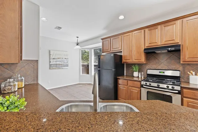 a kitchen with stainless steel appliances granite countertop a refrigerator sink and stove
