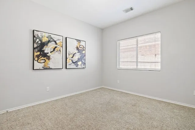 an empty room with a window and painting on the wall