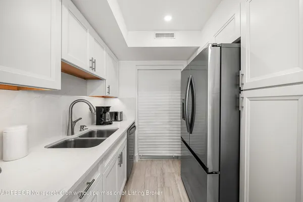 a kitchen with stainless steel appliances a refrigerator sink and white cabinets