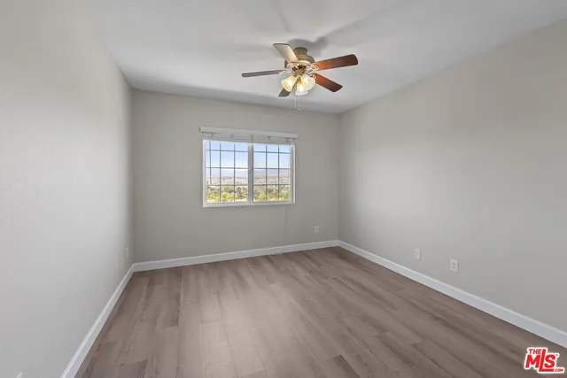 an empty room with wooden floor chandelier and windows