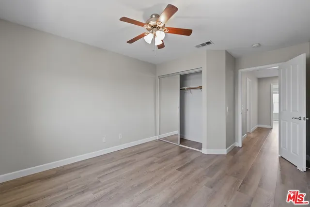 a view of an empty room with window a ceiling fan and wooden floor