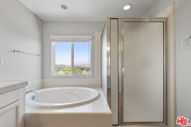 a bathroom with a bathtub a window and a shower