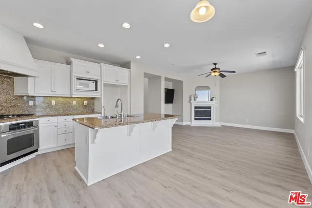 a large kitchen with stainless steel appliances granite countertop a large center island a stove a refrigerator and a sink