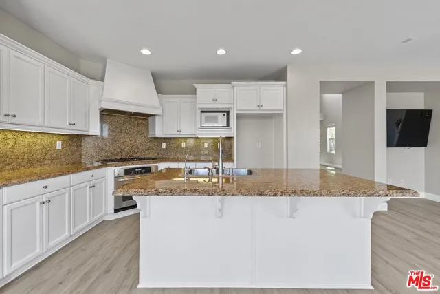 a large kitchen with granite countertop a sink and white cabinets