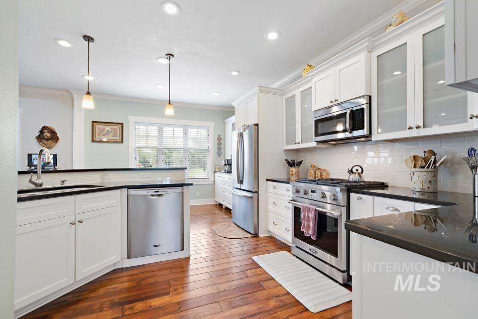 8271 Washoe Road Fruitland, ID 83619 - Photo 17 of 29 Kitchen featuring white cabinetry, dark countertops, wood-finish flooring, stainless steel appliances, and recessed lighting
