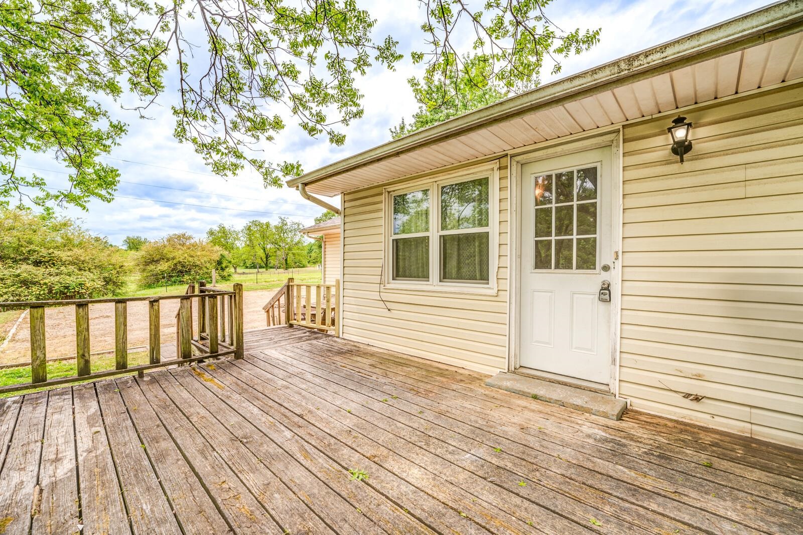 6125 Warren Road Oakland, TN 38060 - Photo 33 of 40 Exterior deck with wood railings, a white paneled door with windowpanes, and an exterior wall light fixture