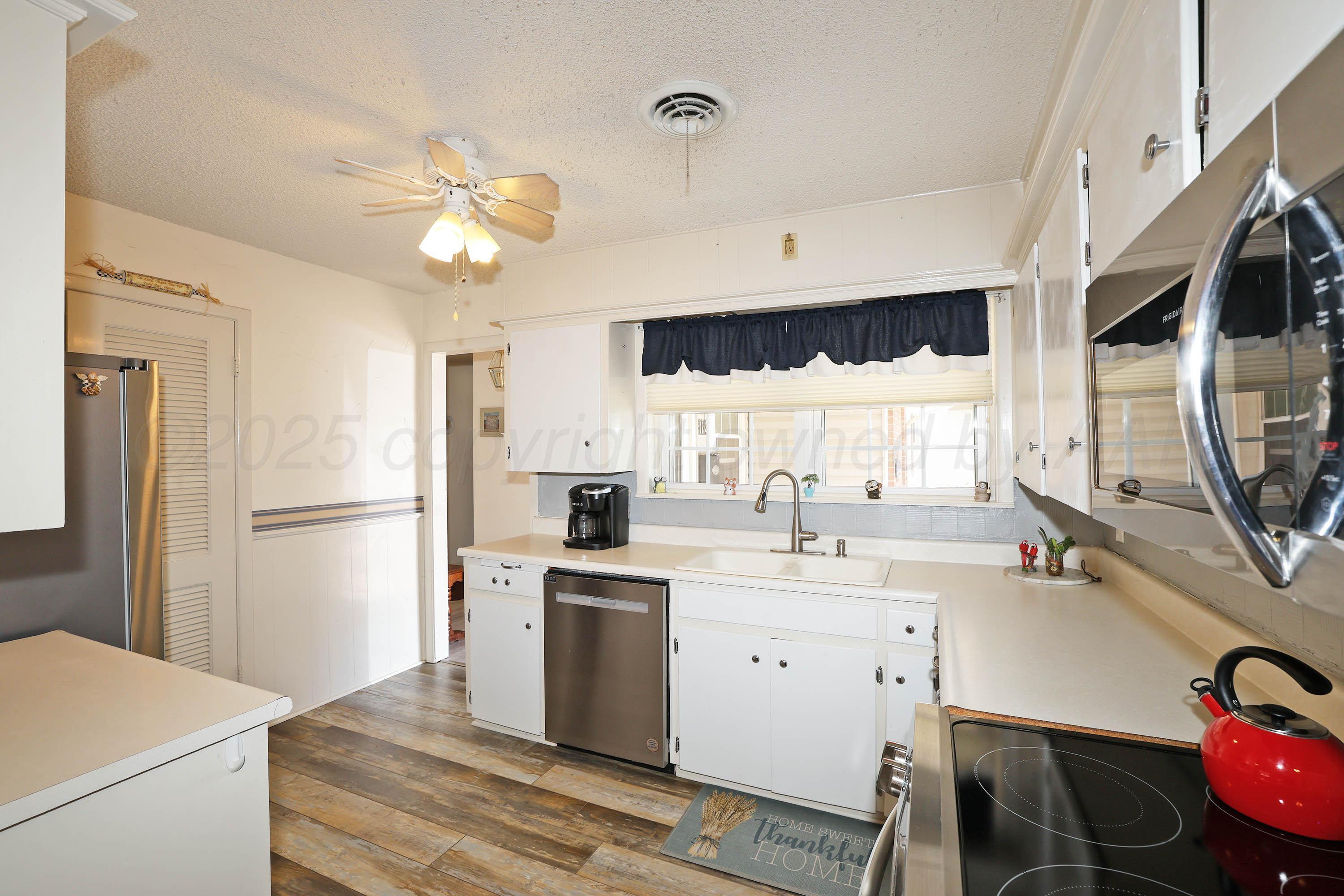 4119 Tucson Drive Amarillo, TX 79109 - Photo 8 of 22 a kitchen with a sink a stove a refrigerator and a fireplace