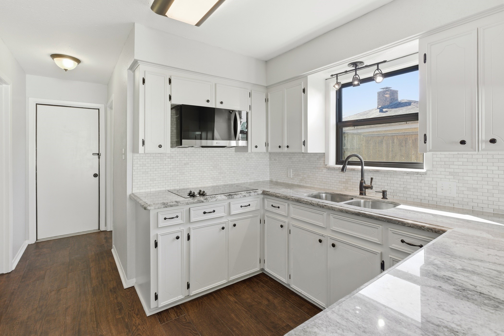 3721 Avenue R Rosenberg, TX 77471 - Photo 15 of 43 Updated kitchen with white cabinetry, granite counters, and stainless steel appliances including refrigerator.