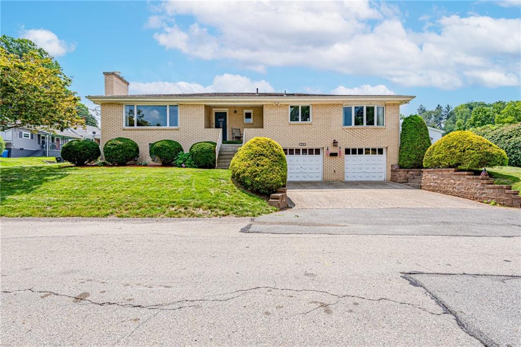 a view of a grey house with a yard and plants