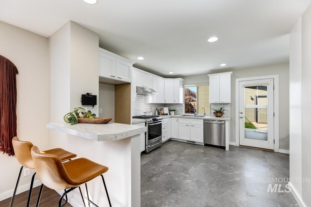 2045 Gourley Street Boise, ID 83705 - Photo 9 of 26 Kitchen with stainless steel appliances, light countertops, white cabinetry, a peninsula, and a kitchen breakfast bar