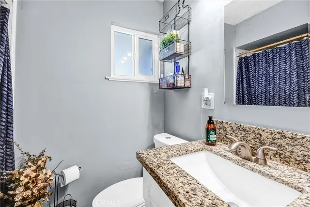 a bathroom with a granite countertop sink a mirror and a toilet