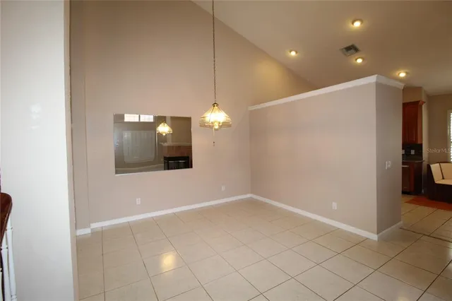 an empty room with kitchen and chandelier