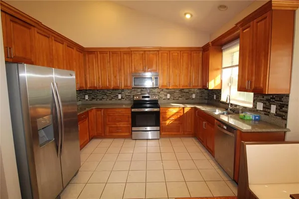 a kitchen with stainless steel appliances granite countertop a stove a sink dishwasher and a refrigerator